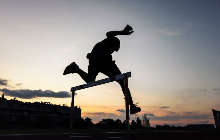 Athlete practicing hurdle techniques at sunset