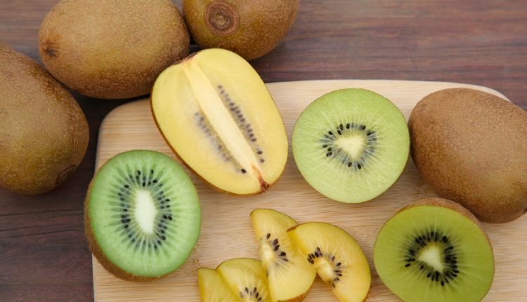 Fresh green and golden kiwi slices on a wooden board