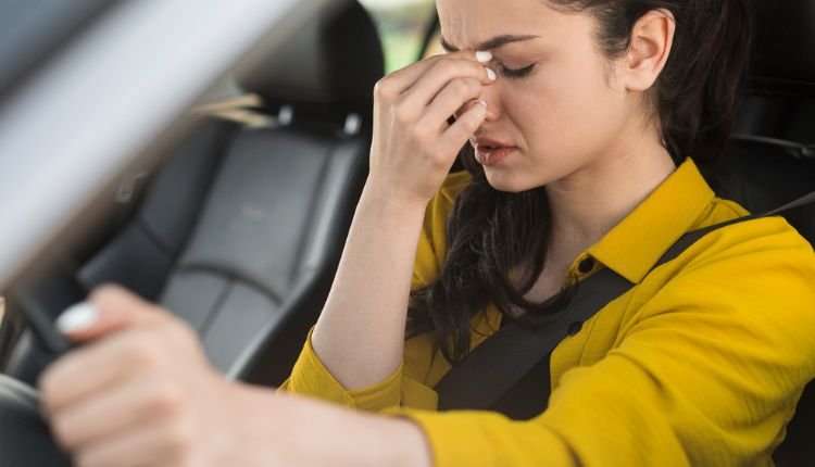 Stressed woman driving, wondering how to get smoke smell out of car.