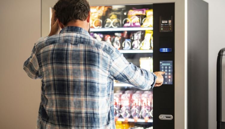 Confused man selecting a snack from a vending machine.