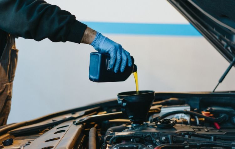 How Long Does Oil Change Take? Mechanic adding fresh oil